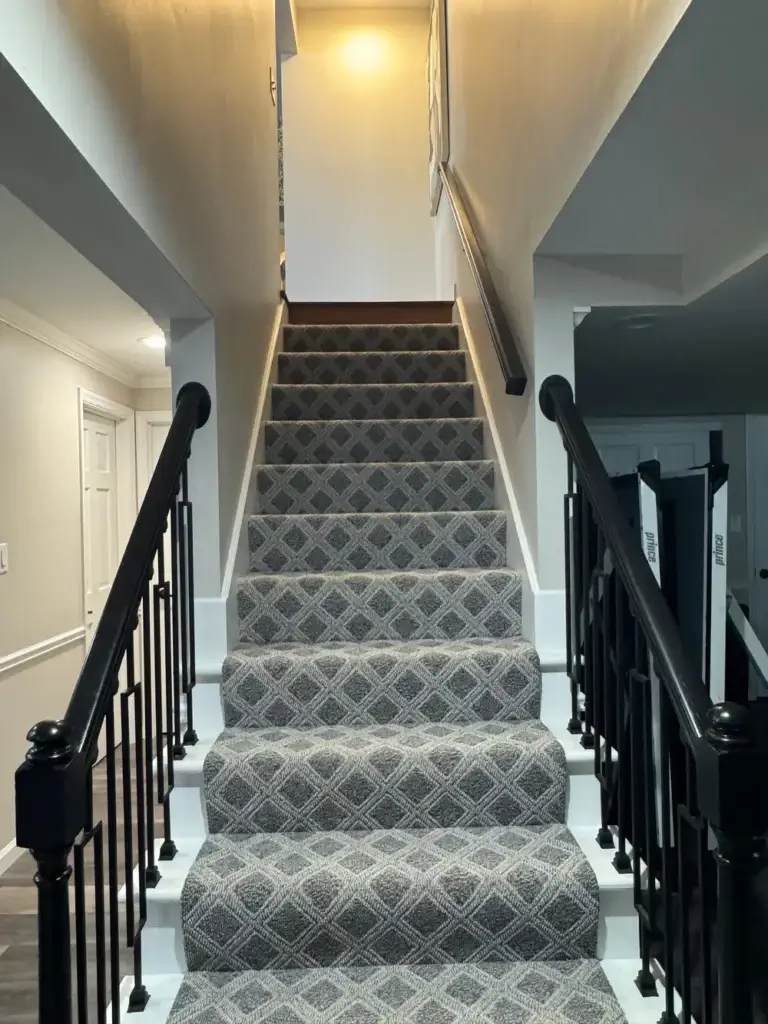 Carpeted staircase with black railings in a remodeled home in St. Louis, MO