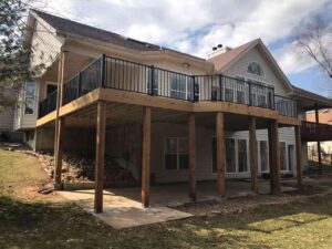 A Two-story house with a wooden deck supported by beams, featuring black railing in St. Louis, MO